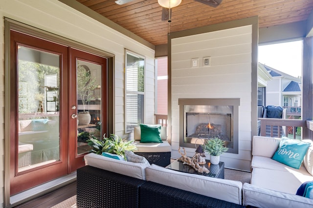 sunroom featuring ceiling fan, plenty of natural light, wooden ceiling, and an outdoor fireplace