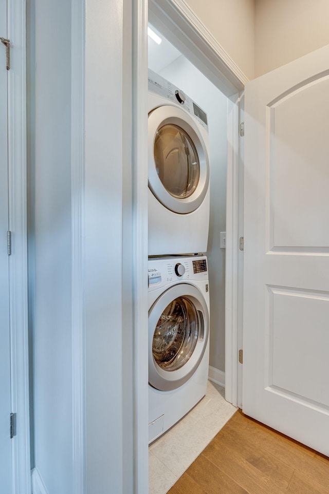 laundry room with light wood-type flooring and stacked washer and clothes dryer