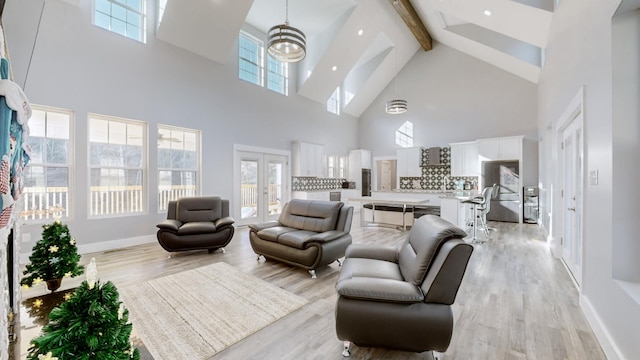 living room with beam ceiling, light wood-type flooring, a towering ceiling, and french doors