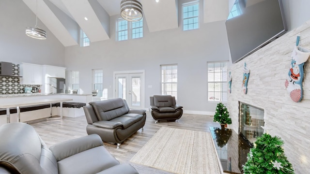 living room with a stone fireplace, a towering ceiling, and a healthy amount of sunlight