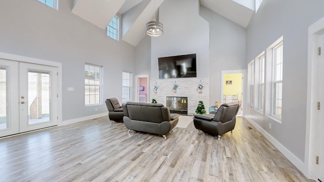 living room with plenty of natural light, a towering ceiling, light hardwood / wood-style flooring, and french doors