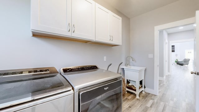 washroom with cabinets, independent washer and dryer, and light hardwood / wood-style floors