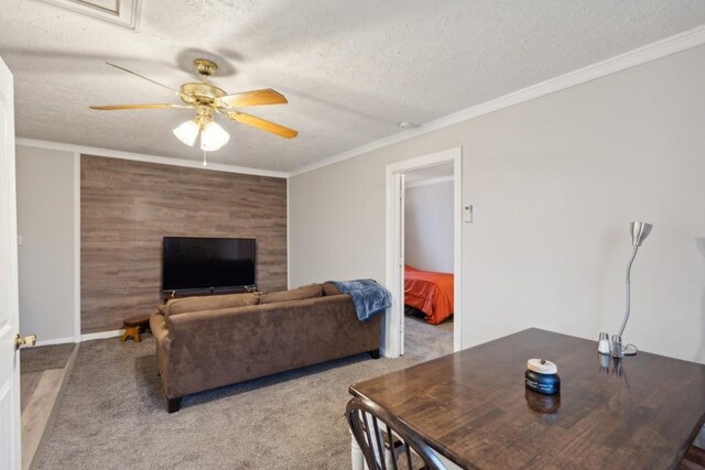 carpeted living room with a textured ceiling, ceiling fan, and crown molding