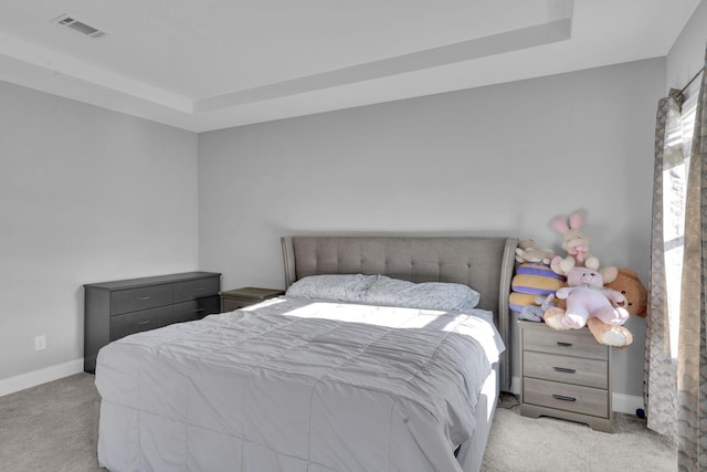 bedroom with light carpet and a tray ceiling