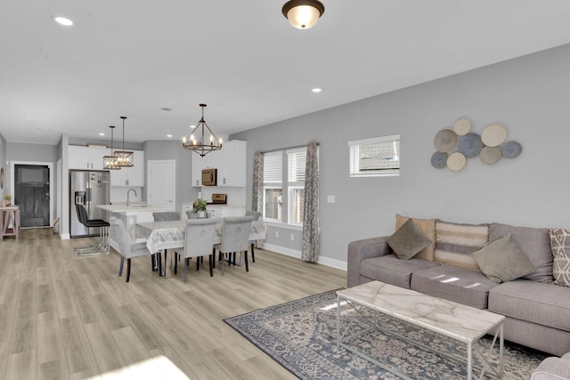 living room with sink, light hardwood / wood-style floors, and a notable chandelier