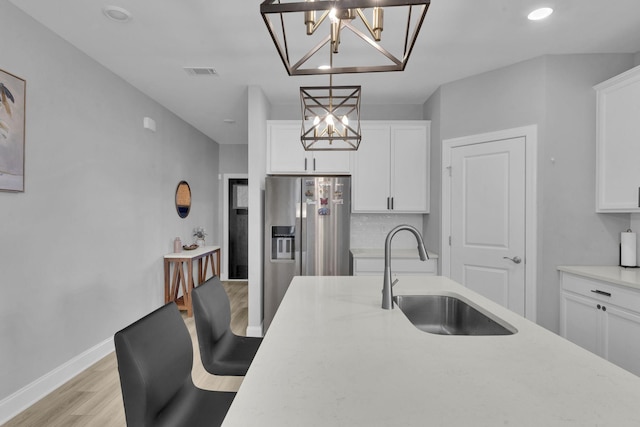 kitchen featuring white cabinetry, sink, stainless steel fridge with ice dispenser, a notable chandelier, and pendant lighting