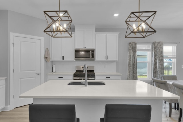 kitchen featuring decorative backsplash, a kitchen island with sink, stainless steel appliances, and hanging light fixtures