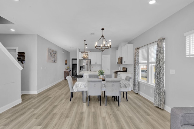 dining area featuring sink, light hardwood / wood-style flooring, and a notable chandelier