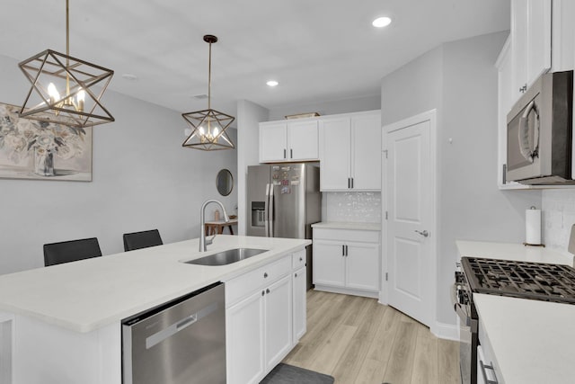 kitchen with appliances with stainless steel finishes, tasteful backsplash, a kitchen island with sink, sink, and pendant lighting