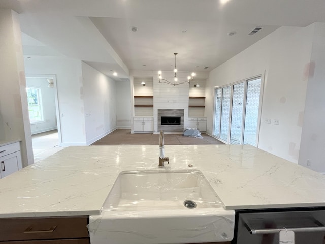 kitchen featuring a kitchen island with sink and light stone countertops