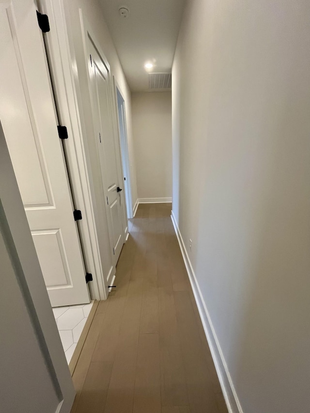 corridor with visible vents, baseboards, and wood finished floors