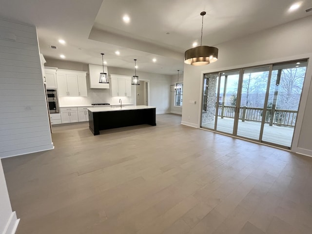 kitchen with open floor plan, light countertops, backsplash, and light wood-style flooring