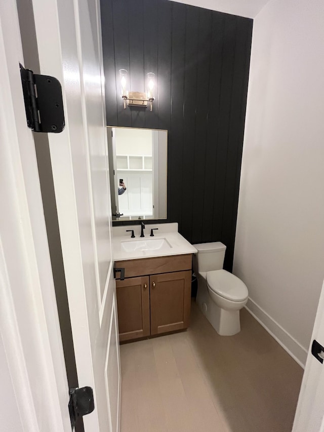 bathroom featuring toilet, baseboards, and vanity