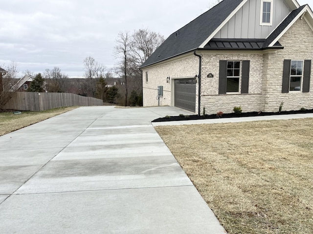 view of home's exterior featuring board and batten siding, a standing seam roof, metal roof, fence, and driveway