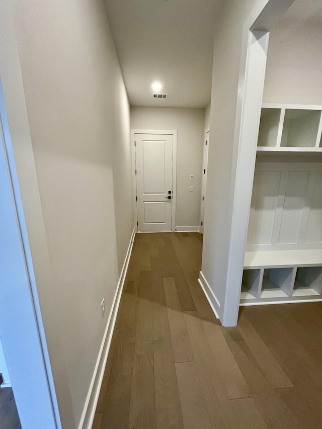 hallway featuring visible vents, dark wood finished floors, and baseboards