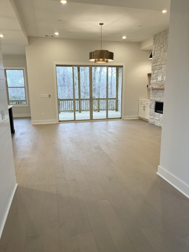 unfurnished living room featuring recessed lighting, a fireplace, baseboards, and wood finished floors