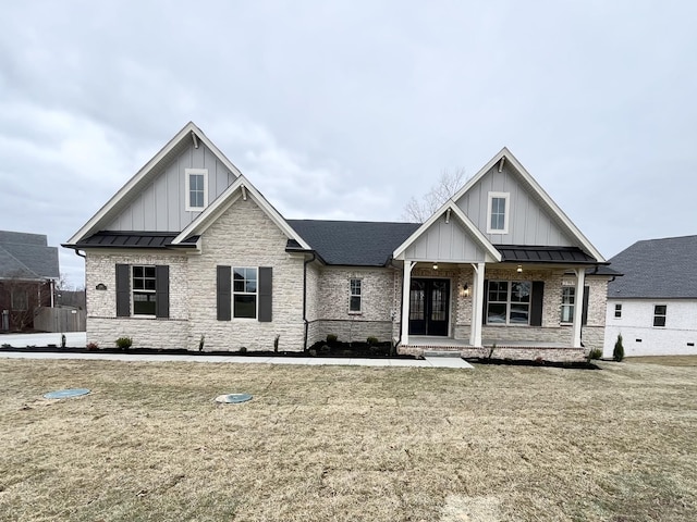 view of front of property with metal roof, brick siding, board and batten siding, a front lawn, and a standing seam roof