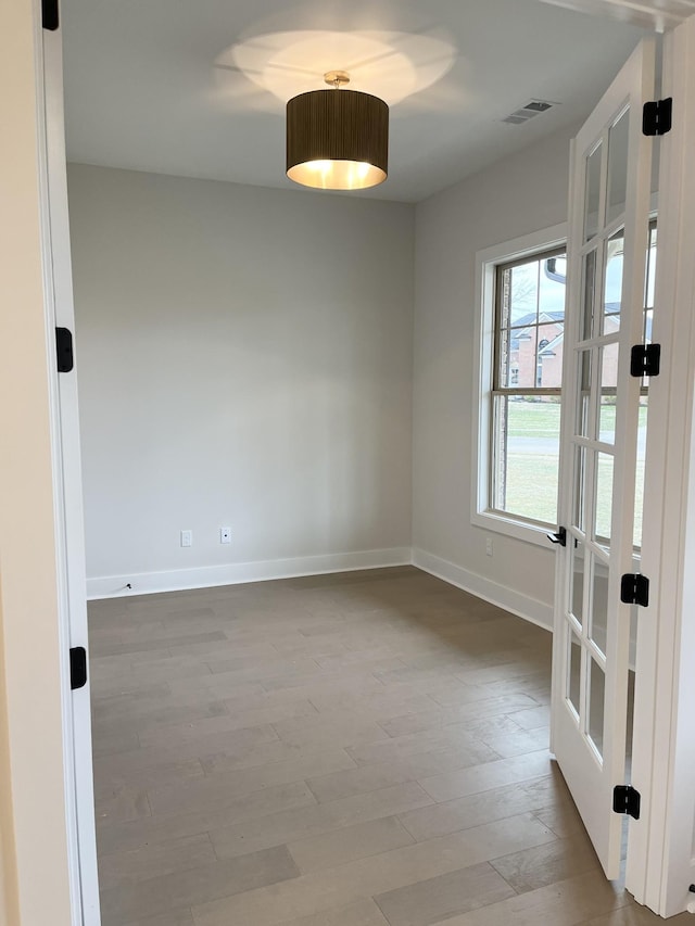 empty room with baseboards, visible vents, and wood finished floors