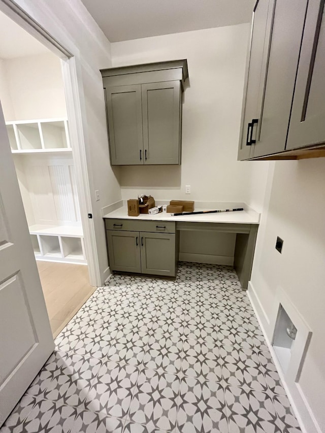 clothes washing area with light floors and baseboards