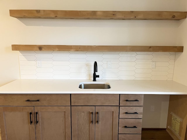 kitchen featuring tasteful backsplash, light countertops, and a sink