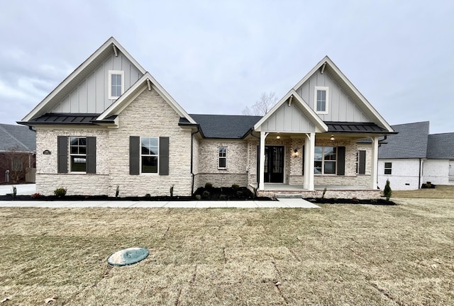 view of front of home with brick siding, metal roof, a standing seam roof, board and batten siding, and a front yard