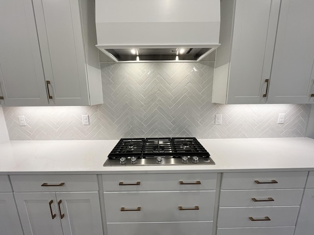 kitchen featuring custom range hood, light countertops, backsplash, and stainless steel gas stovetop