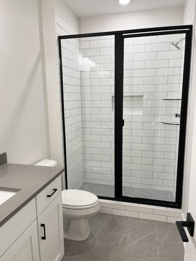 bathroom featuring vanity, a shower stall, and toilet