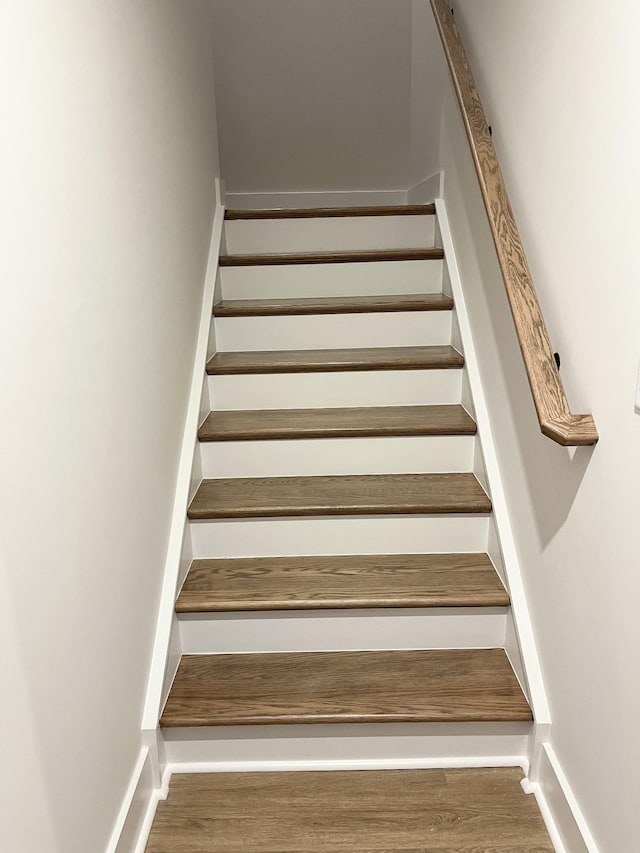 staircase with baseboards and wood finished floors