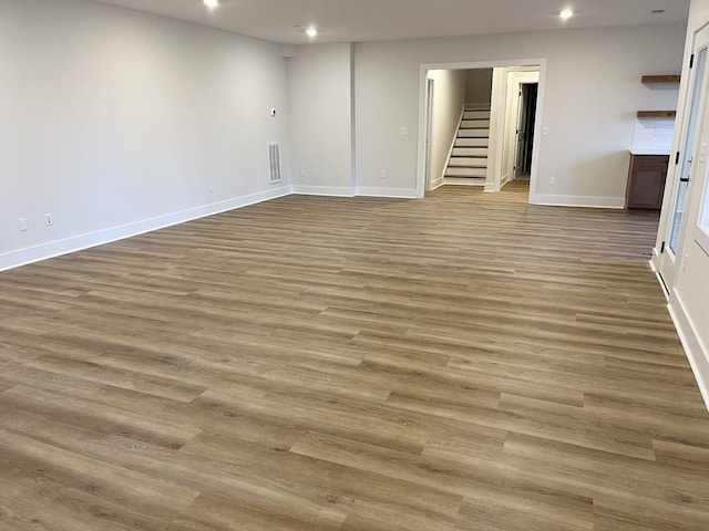 below grade area with recessed lighting, visible vents, wood finished floors, baseboards, and stairs