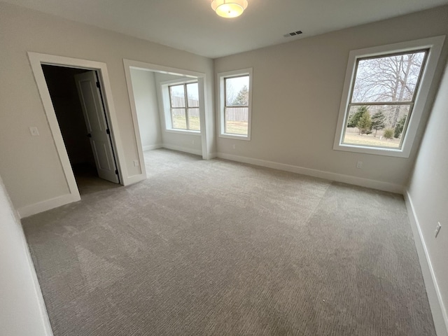 unfurnished bedroom featuring visible vents, light colored carpet, and baseboards