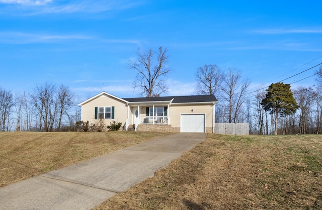 ranch-style home featuring a garage, covered porch, and a front yard