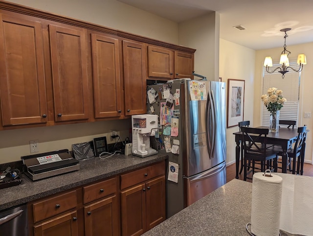 kitchen featuring a notable chandelier, dark stone countertops, hanging light fixtures, and appliances with stainless steel finishes