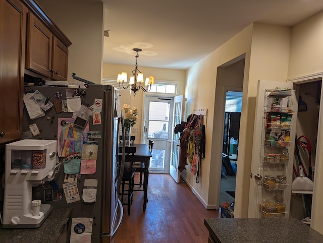 kitchen with dark hardwood / wood-style floors, stainless steel refrigerator, hanging light fixtures, and a notable chandelier