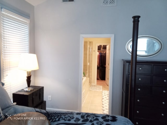 bedroom featuring light tile patterned floors and a walk in closet