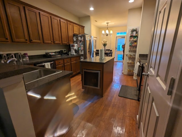 kitchen with dark wood-type flooring, sink, hanging light fixtures, a kitchen island, and a chandelier