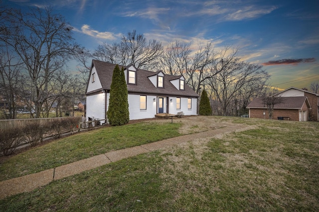 cape cod house featuring a lawn