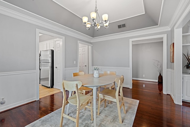 dining space with a chandelier, hardwood / wood-style floors, a tray ceiling, and crown molding