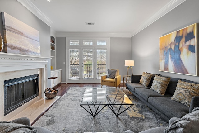 living room with built in shelves, crown molding, and wood-type flooring