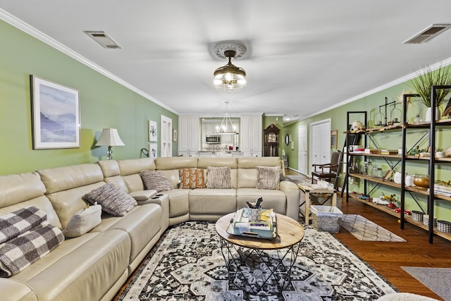 living room with hardwood / wood-style flooring, ornamental molding, and an inviting chandelier