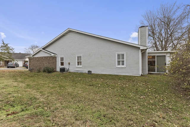 view of side of property with a yard, central air condition unit, and a sunroom