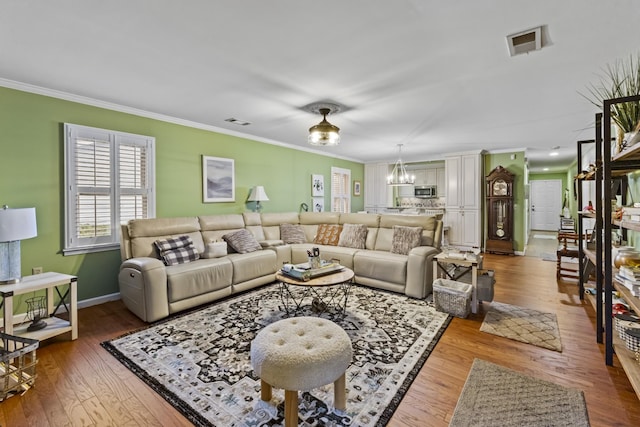 living room featuring crown molding, wood-type flooring, and a notable chandelier