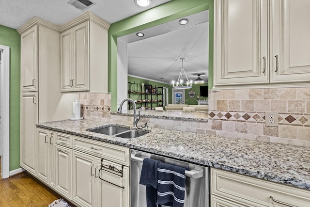 kitchen with dishwasher, sink, light stone counters, light hardwood / wood-style floors, and cream cabinetry