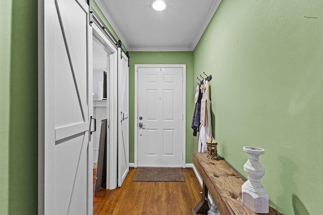 entryway with a barn door, wood-type flooring, and crown molding