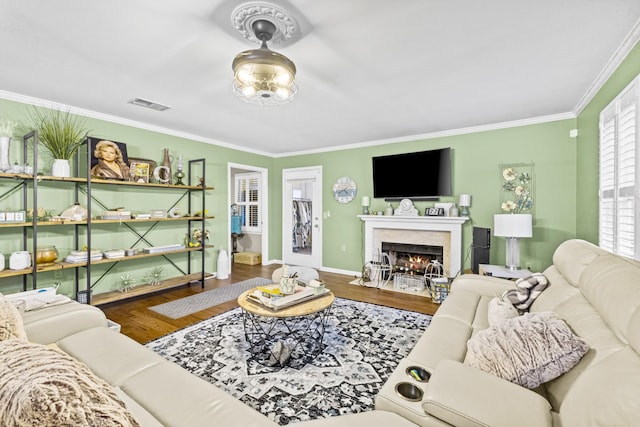 living room with a premium fireplace, crown molding, and hardwood / wood-style flooring