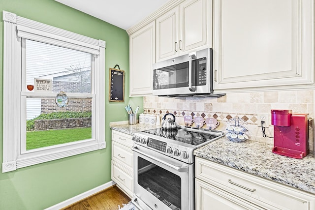 kitchen featuring white cabinets, decorative backsplash, light stone countertops, and appliances with stainless steel finishes