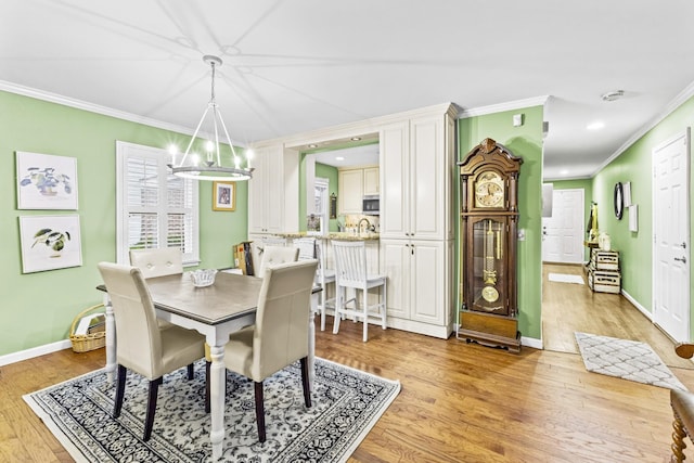 dining space with light wood-type flooring, crown molding, and a notable chandelier