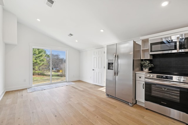 kitchen featuring lofted ceiling, stainless steel appliances, light hardwood / wood-style floors, and backsplash