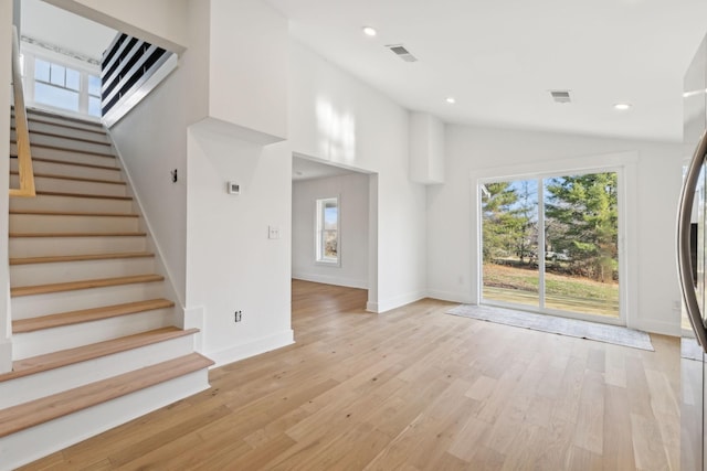 unfurnished living room with light hardwood / wood-style flooring, lofted ceiling, and plenty of natural light