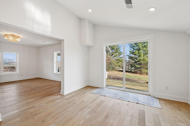 unfurnished living room featuring light hardwood / wood-style flooring, vaulted ceiling, and plenty of natural light