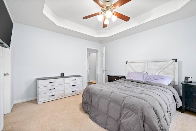 bedroom featuring ceiling fan, a tray ceiling, and light colored carpet